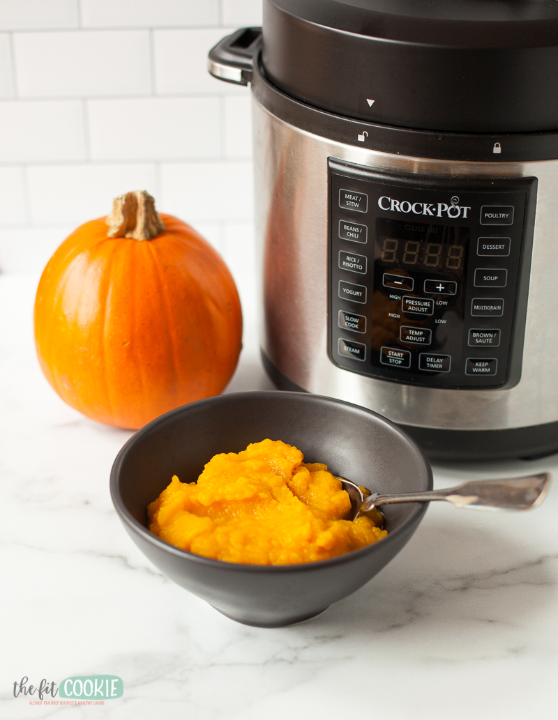 A bowl of pumpkin puree next to a crock pot pressure cooker.