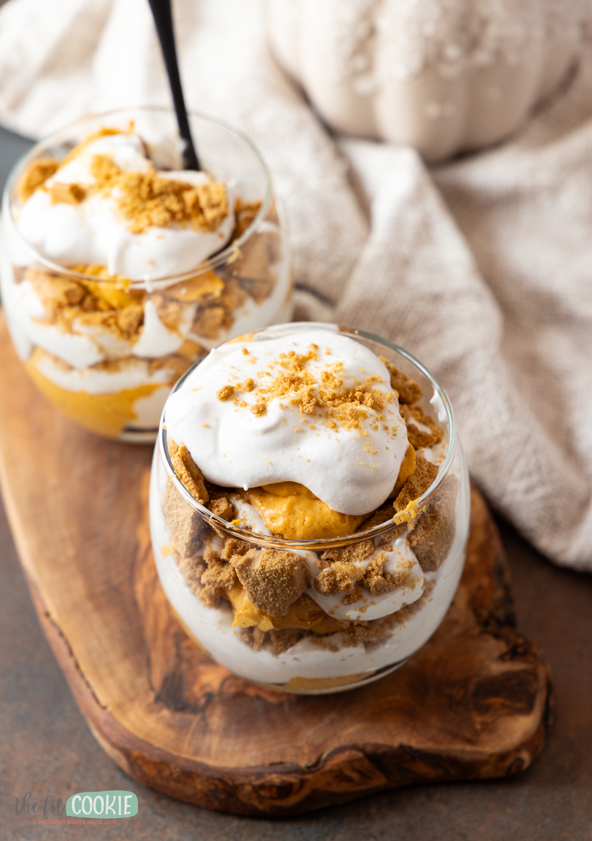 A delightful pumpkin trifle adorned with fluffy whipped cream and showcased against a backdrop of pumpkins.