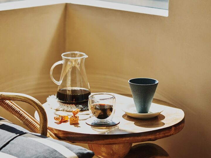 A cup of coffee on a table next to a window.