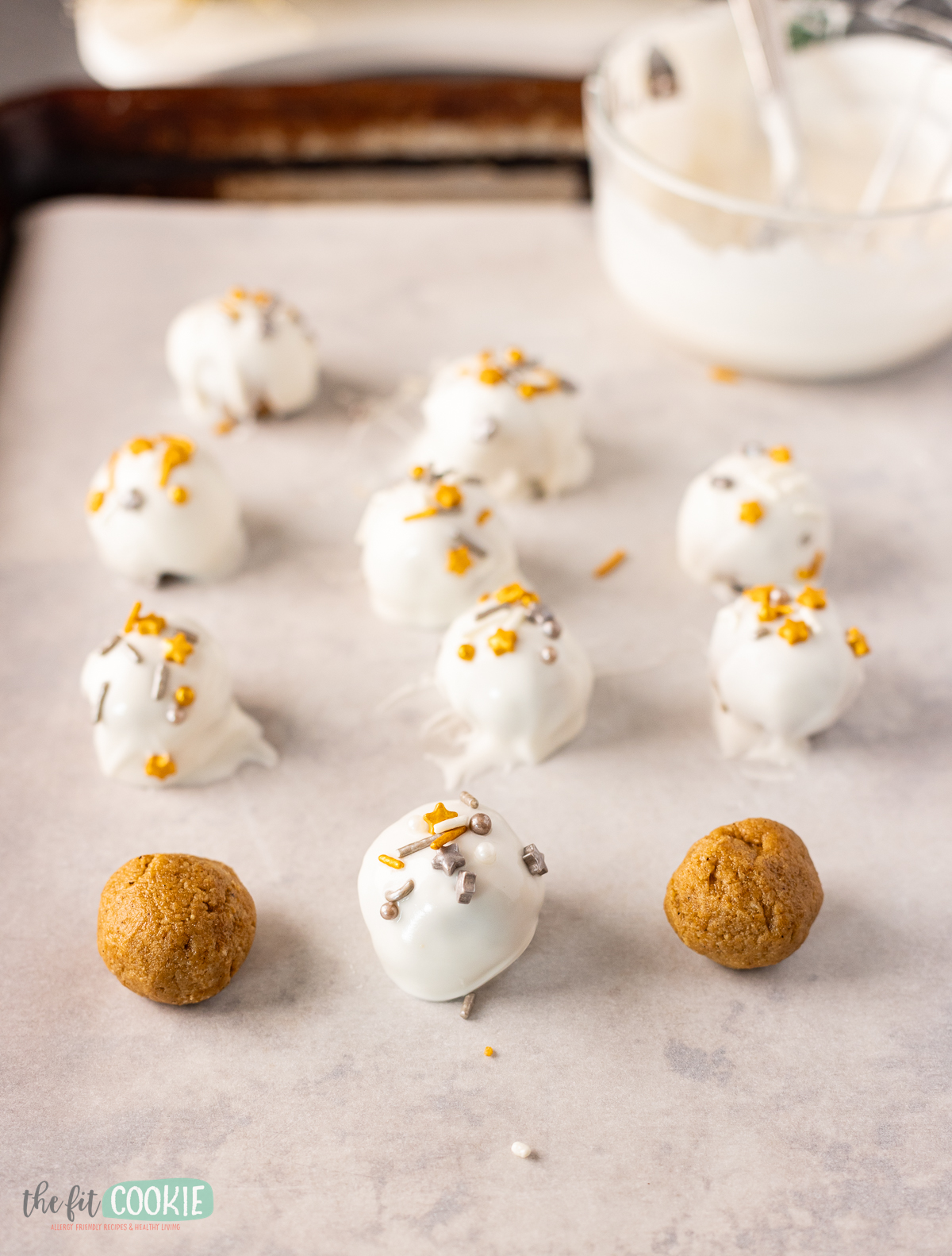 A baking sheet with dairy free Gingerbread Oreo Truffles with white chocolate and sprinkles.
