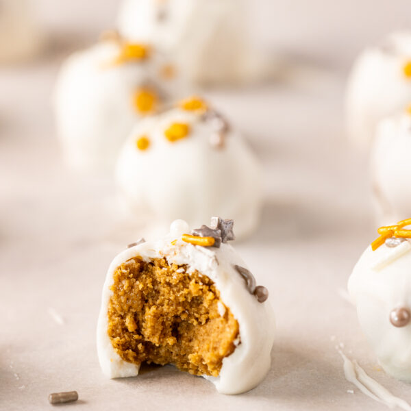White chocolate pumpkin truffles with a bite taken out of them, infused with gingerbread flavors.