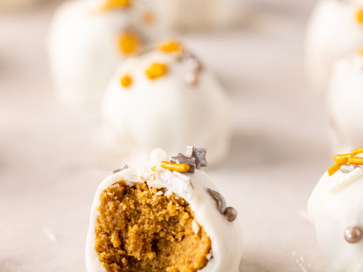 White chocolate pumpkin truffles with a bite taken out of them, infused with gingerbread flavors.