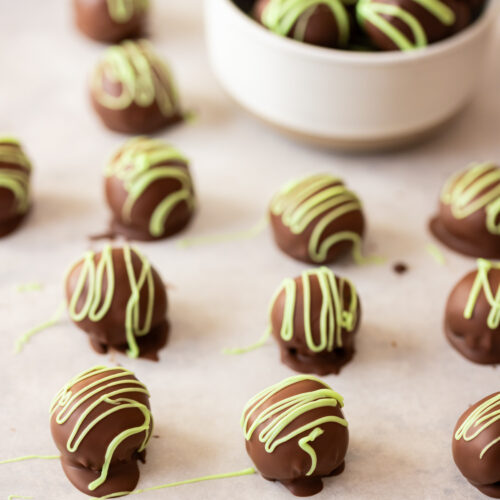 Chocolate truffles with green sprinkles on a baking sheet.
