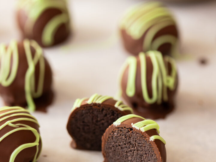 Chocolate truffles with green icing and a bite taken out.