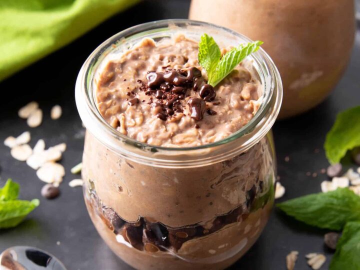Two jars filled with chocolate pudding and mint leaves.