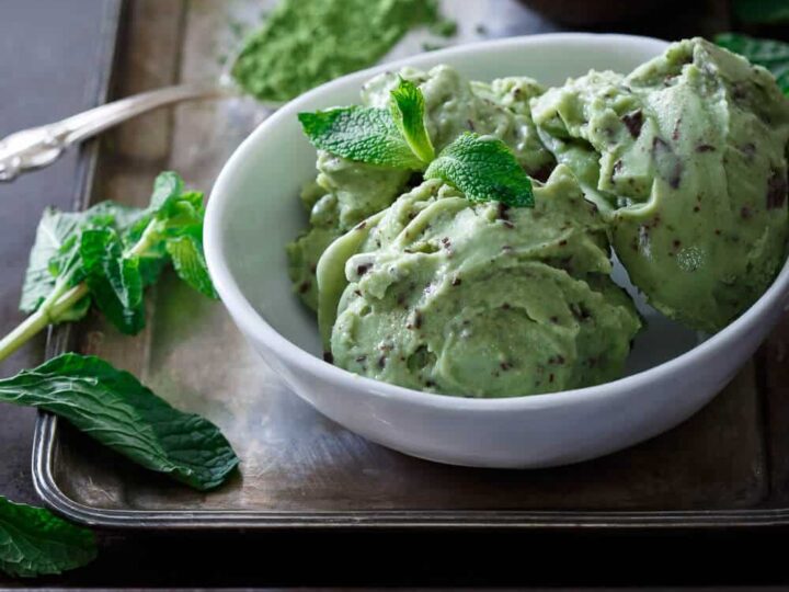 Mint chocolate ice cream in a bowl with mint leaves.