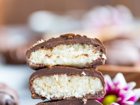 A stack of chocolate coconut bars with flowers in the background.