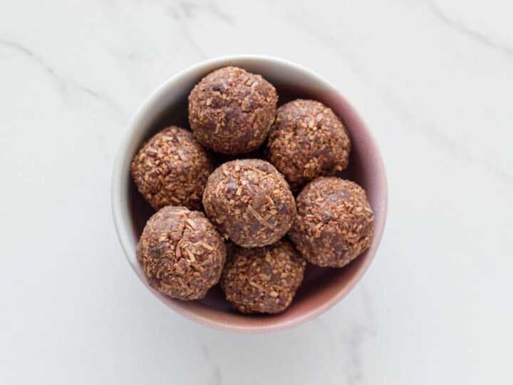 Chocolate energy balls in a bowl on a marble table.