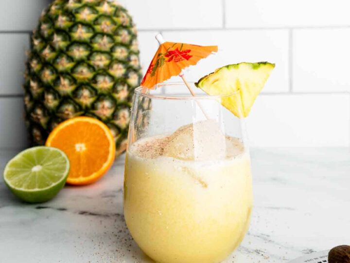 A drink with a pineapple on top and a lime on the side.