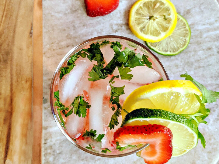 A glass of drink with fruit slices on a plate.