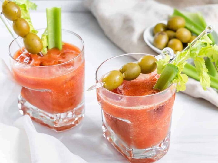 Two glasses of bloody mary with olives and celery.