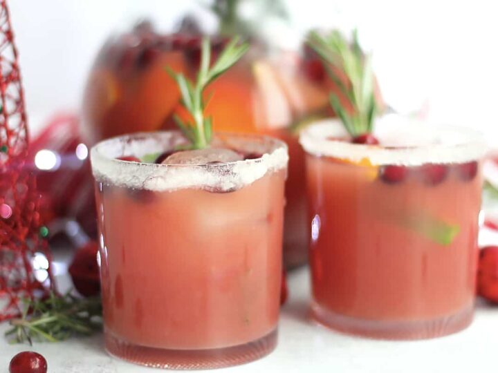 Two glasses of cranberry sangria with rosemary sprigs.