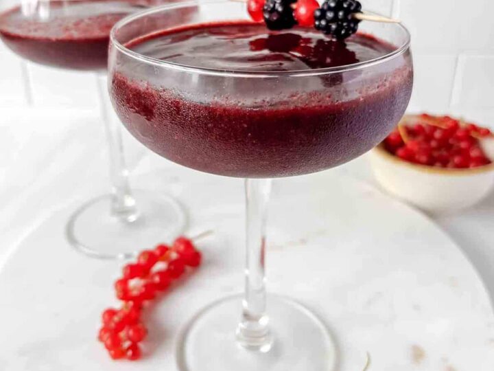 Two martinis with berries and berries on a white plate.