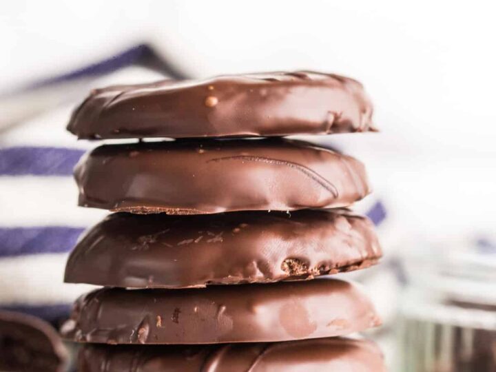A stack of chocolate covered cookies with mint leaves.