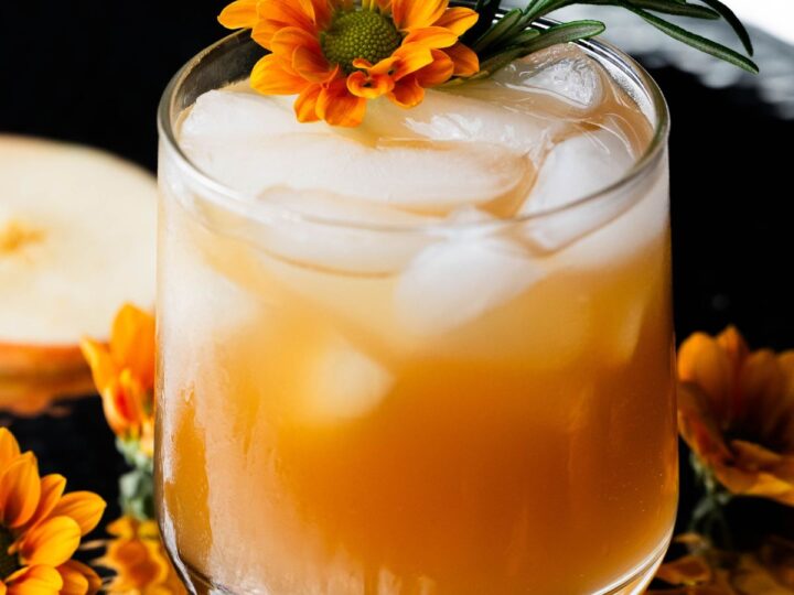 A cocktail with orange flowers and ice in a glass.