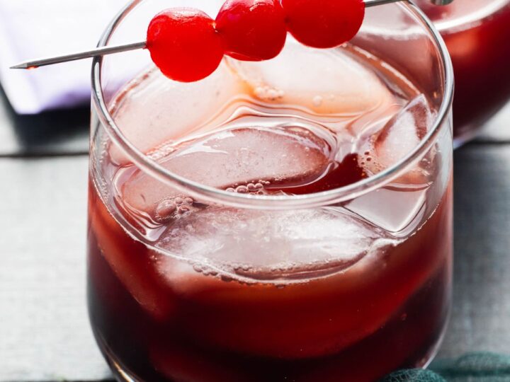 A cocktail with cherries and ice in a glass.