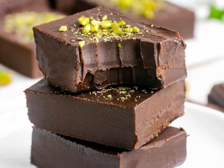 A stack of chocolate fudge on a plate with pistachios.
