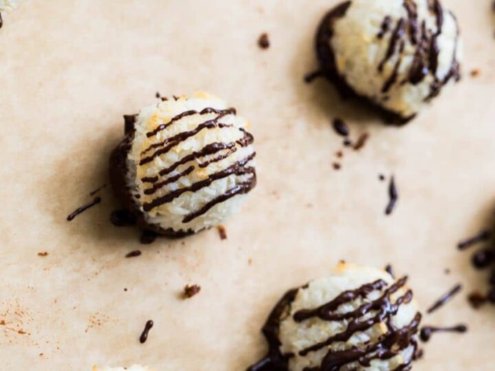 Coconut macaroons with chocolate drizzle on a baking sheet.