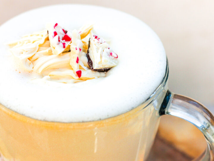 A latte with whipped cream and sprinkles on top.