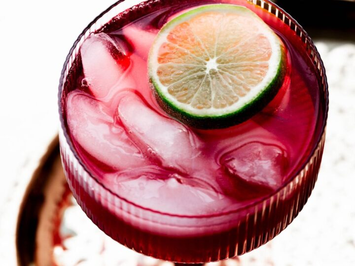 A cocktail with ice and lime on a tray.