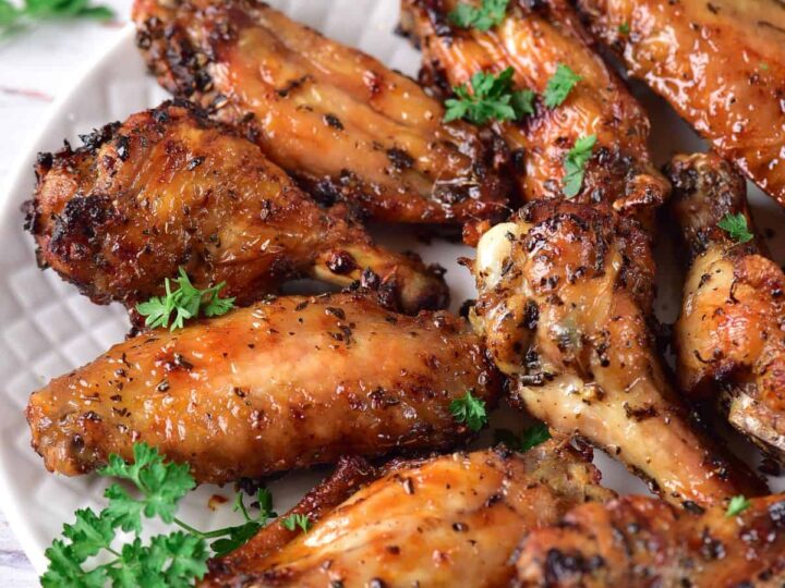 Chicken wings on a plate with carrots and parsley.