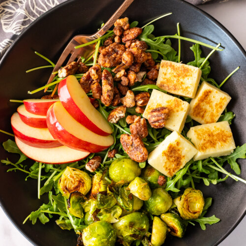 A winter salad bowl with apples, brussel sprouts and tofu.