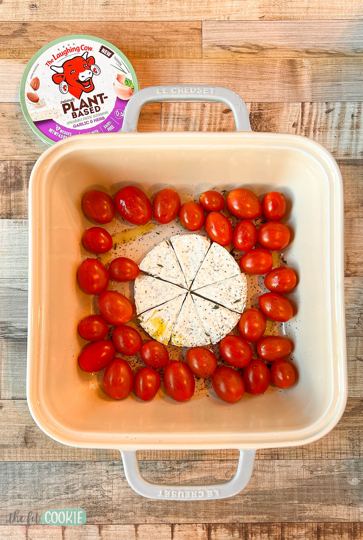 A square baking dish with tomatoes and laughing cow spreadable cheese.