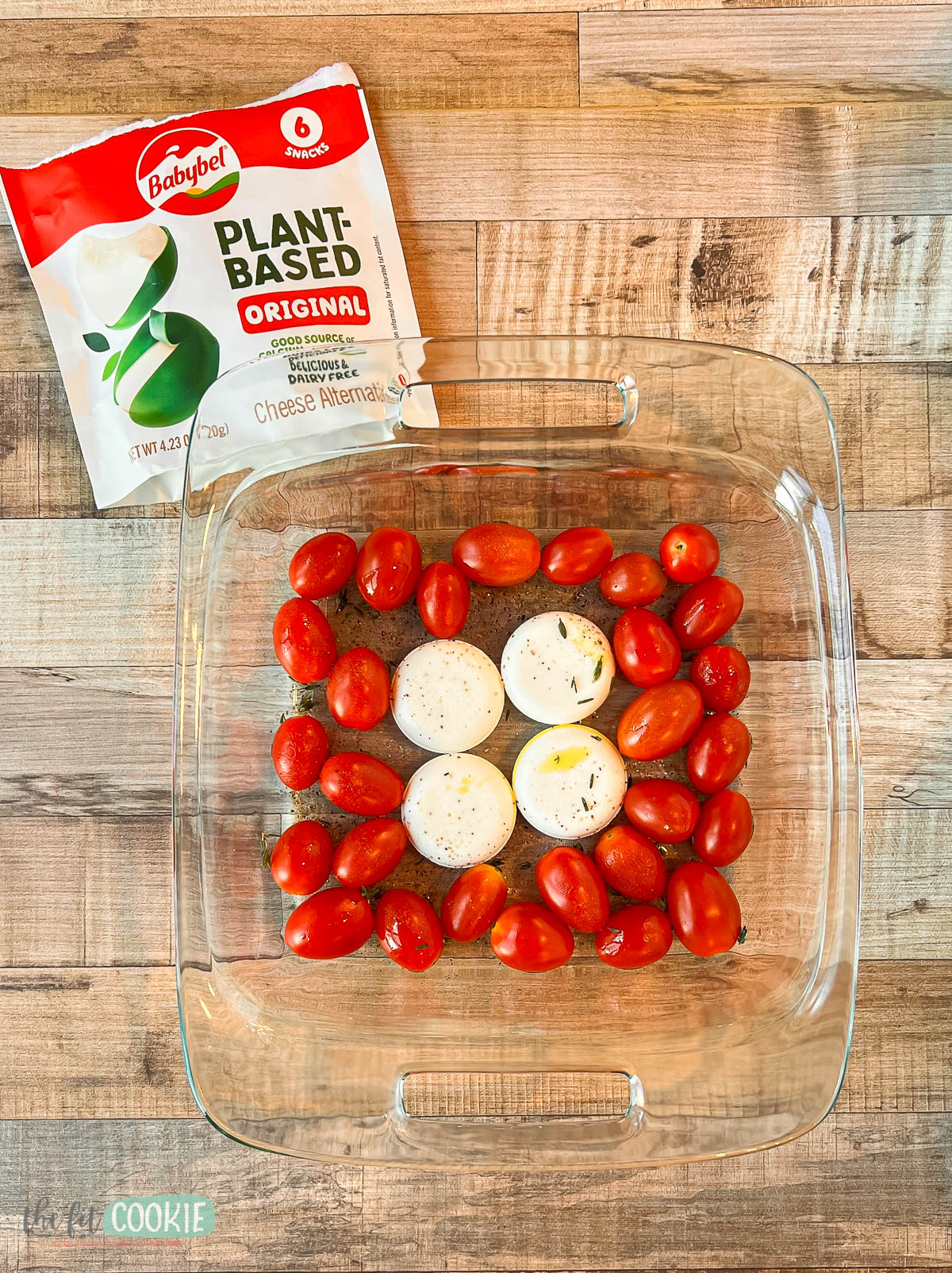 a glass baking dish with babybel plant based cheese and tomatoes.
