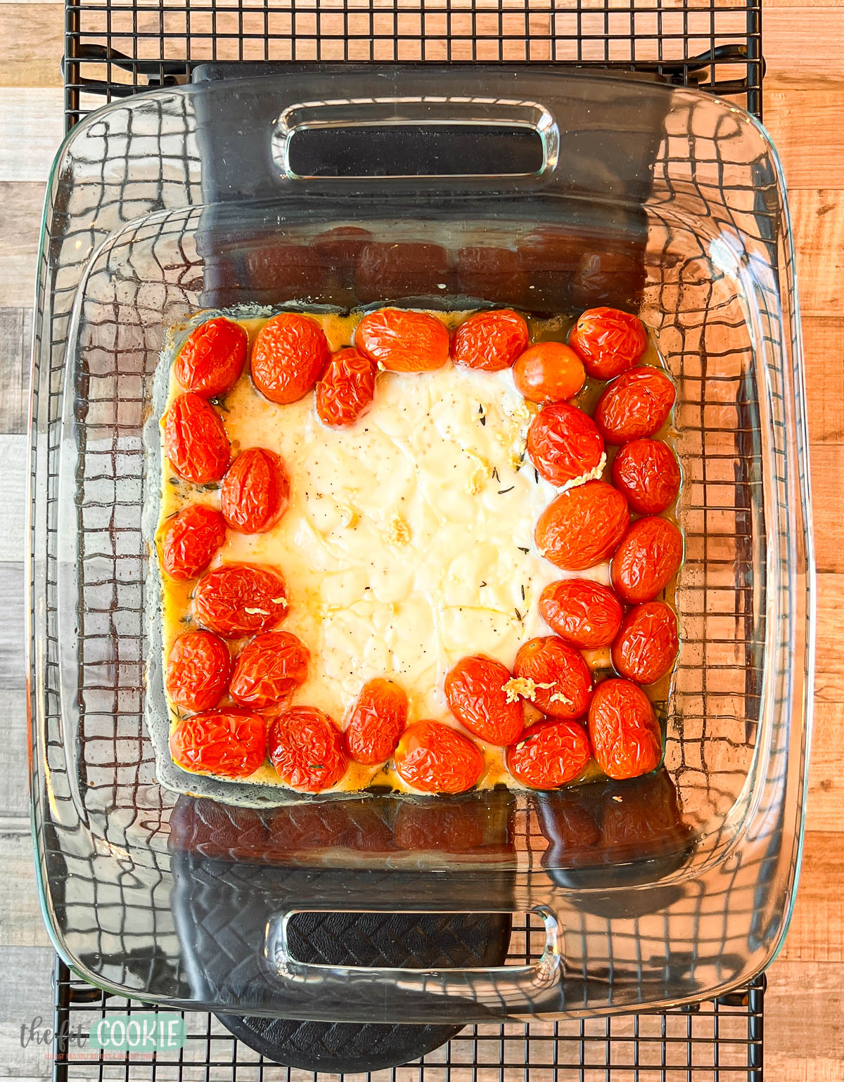 A glass baking dish with roasted cherry tomatoes and dairy free cheese.