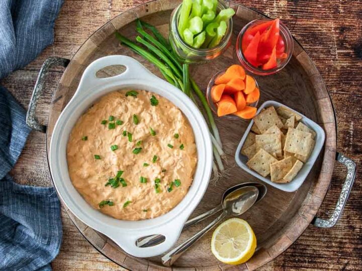 A bowl of chicken dip on a wooden platter.