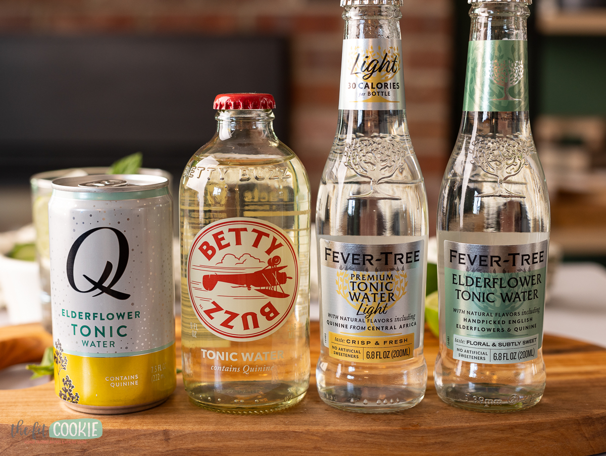Bottles of different brands of tonic water on a cutting board.