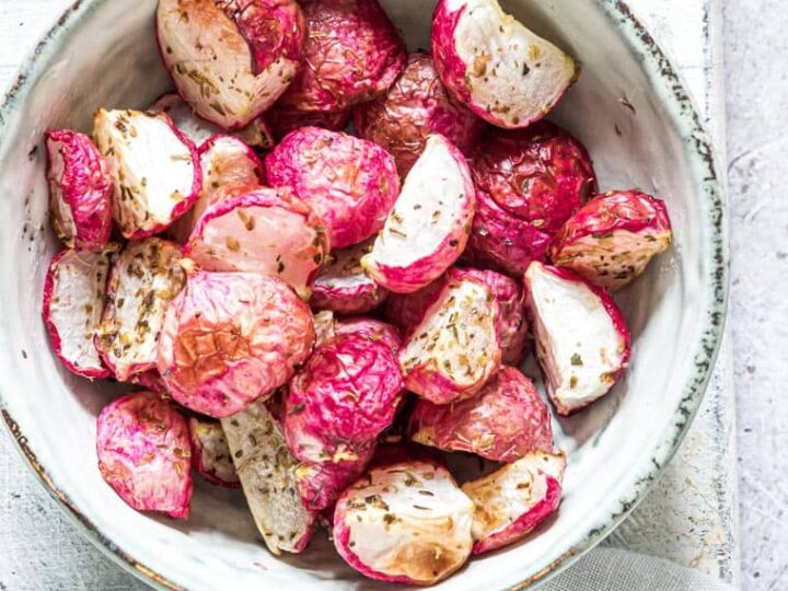 Roasted radishes in a bowl on a white background.