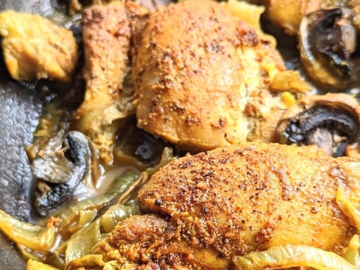 Chicken in a skillet with mushrooms and onions.