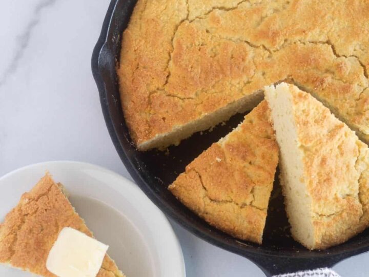 Cornbread in a skillet with a slice taken out.