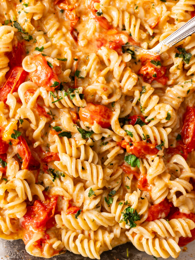 A bowl of pasta with tomatoes and parsley.