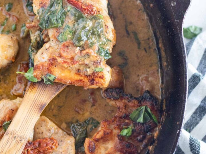 A skillet with chicken and spinach in it.