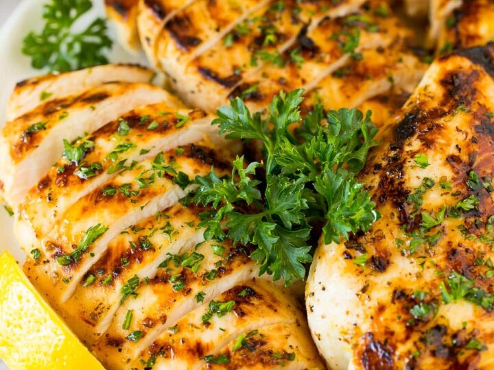Grilled chicken with lemon and parsley on a plate.