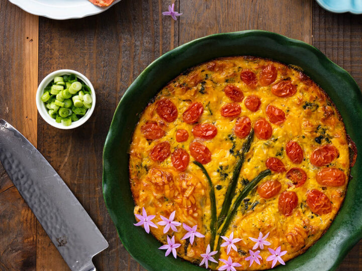 A green bowl filled with a quiche and a knife.