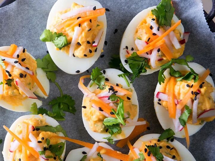 Deviled eggs with carrots and cilantro on a plate.