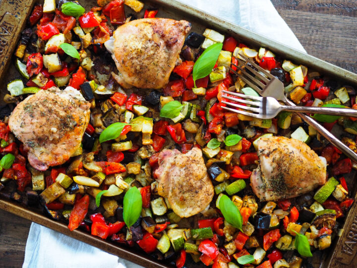 Roasted chicken and vegetables on a baking sheet.