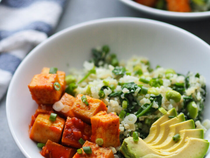 Two bowls with tofu, avocado and greens.