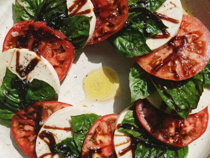 A plate of tomato, mozzarella and basil on a wooden table.