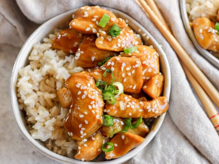 Asian chicken in a bowl with rice and chopsticks.