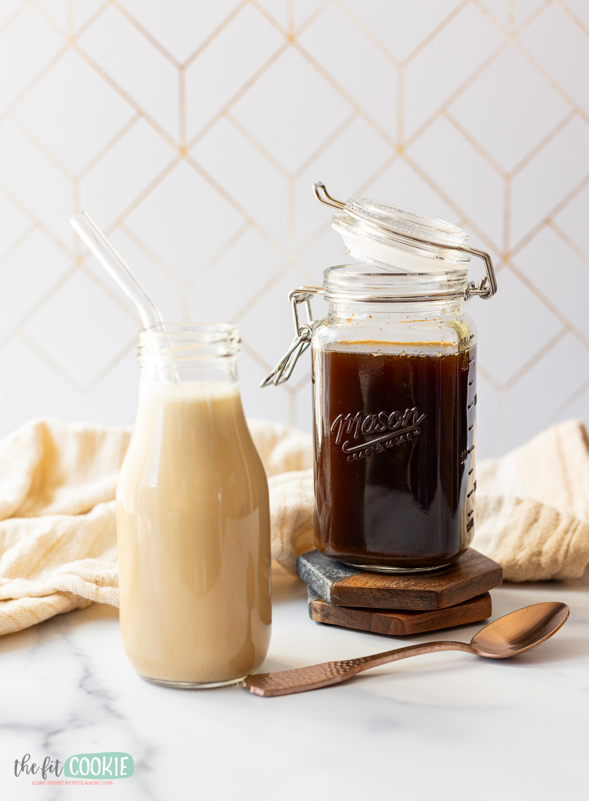 a bottle of oat milk chai latte next to a jar of homemade chai syrup. 