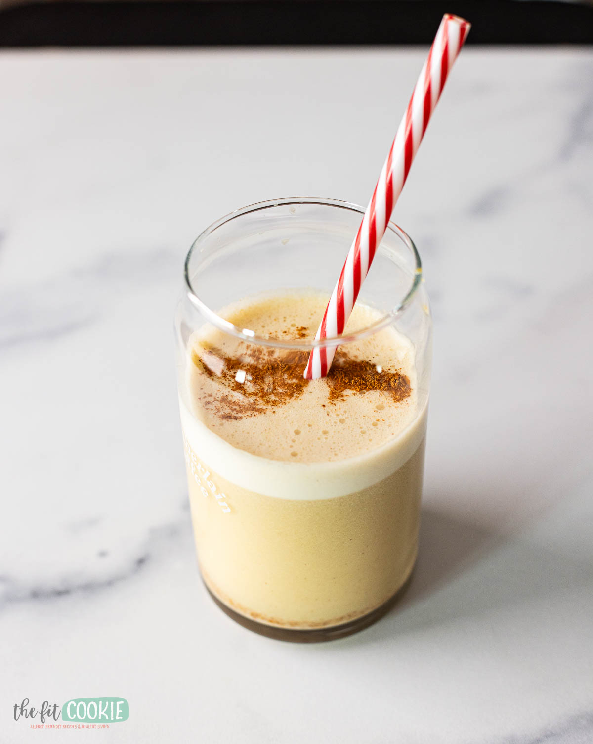 a glass of snickerdoodle protein shake with a red striped straw. 