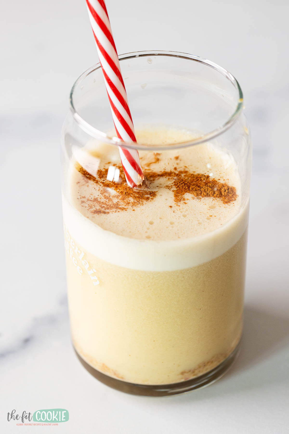 A glass with a snickerdoodle smoothie with cinnamon on top. 