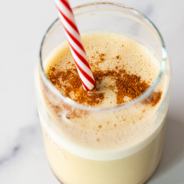 A Snickerdoodle Cookie Smoothie served with a red and white striped straw.