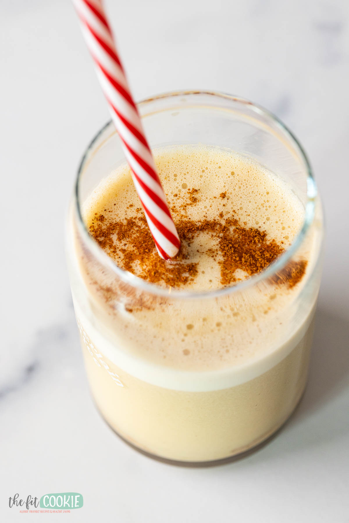 A Snickerdoodle Cookie Smoothie served with a red and white striped straw.