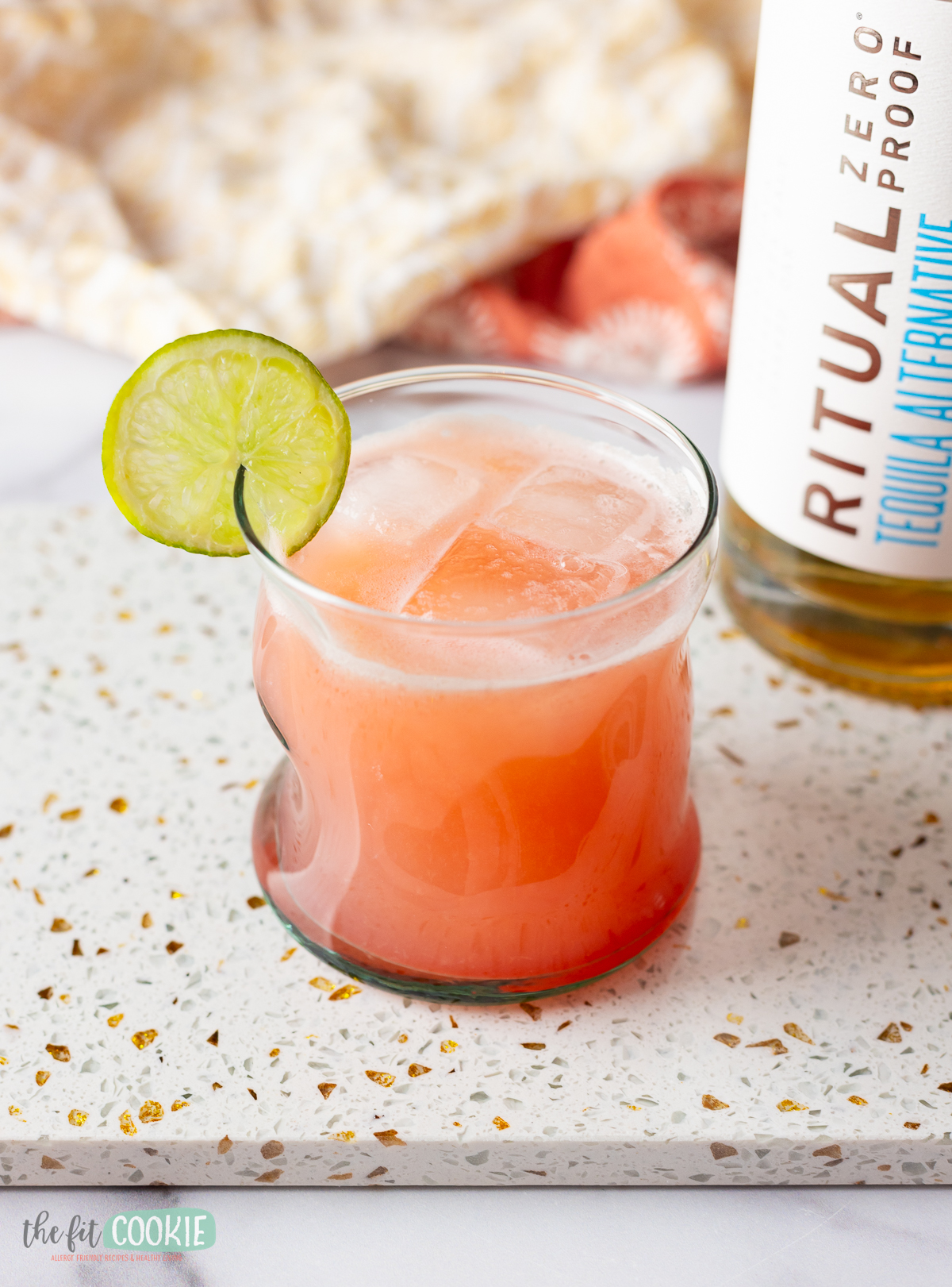 A glass with a lime on it next to a bottle of rum, perfect for making a refreshing Paloma cocktail.