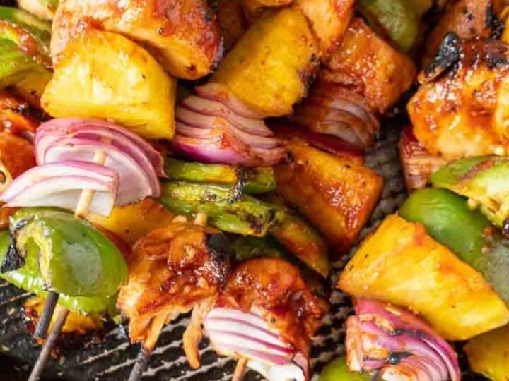 Chicken and pineapple kabobs on a grill.
